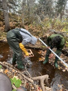 Crew using gravelometer to measure the pebble, cobble, rock size in the stream.